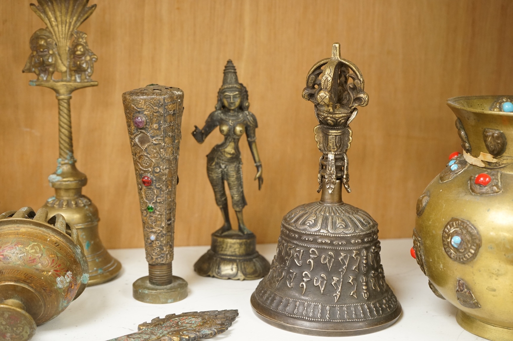 A group of Tibetan brass and mixed metal artefacts to include a brass vase with cabochon inset stones and figures of deities, largest 22cm high